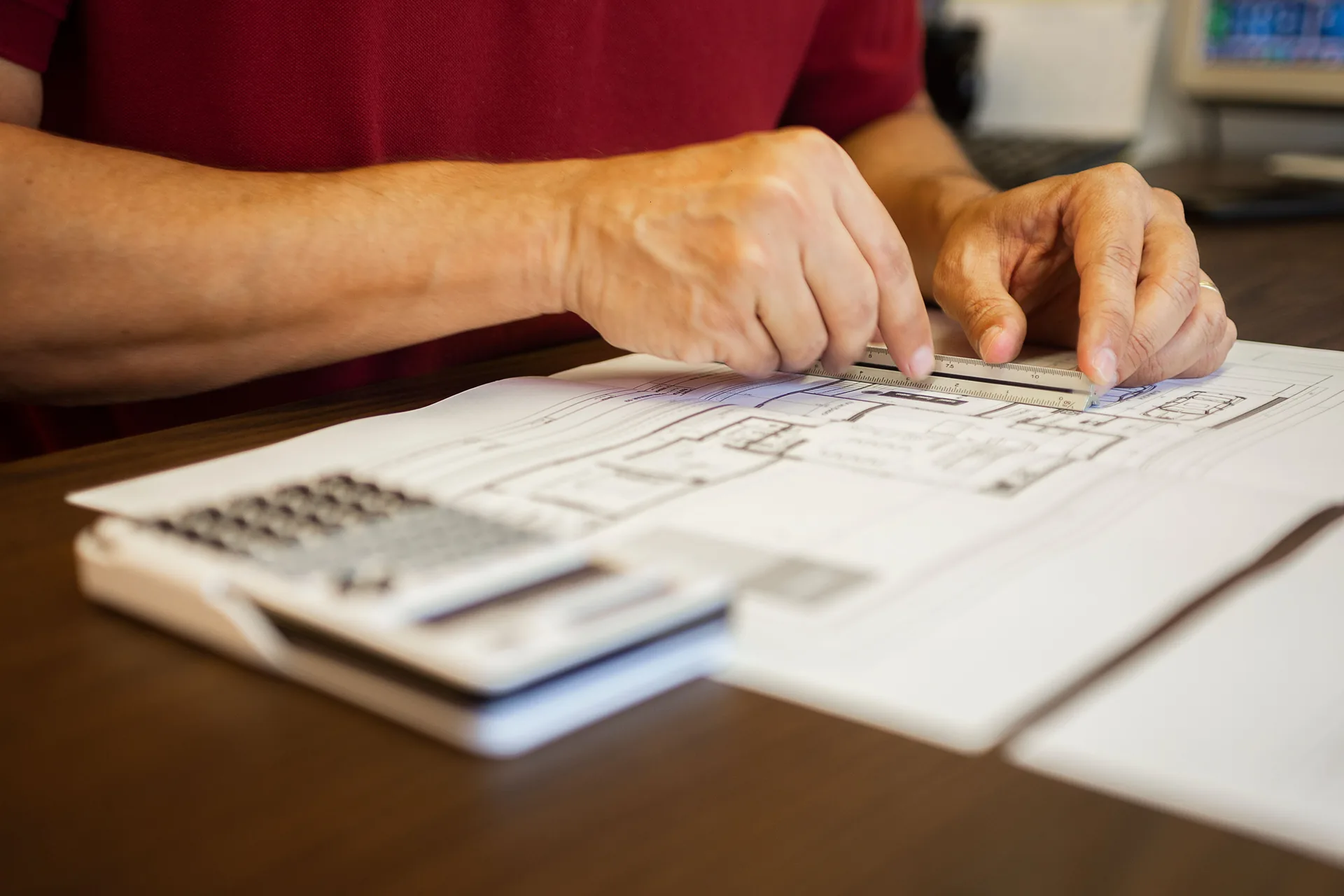 Hands reviewing architectural plans with a ruler