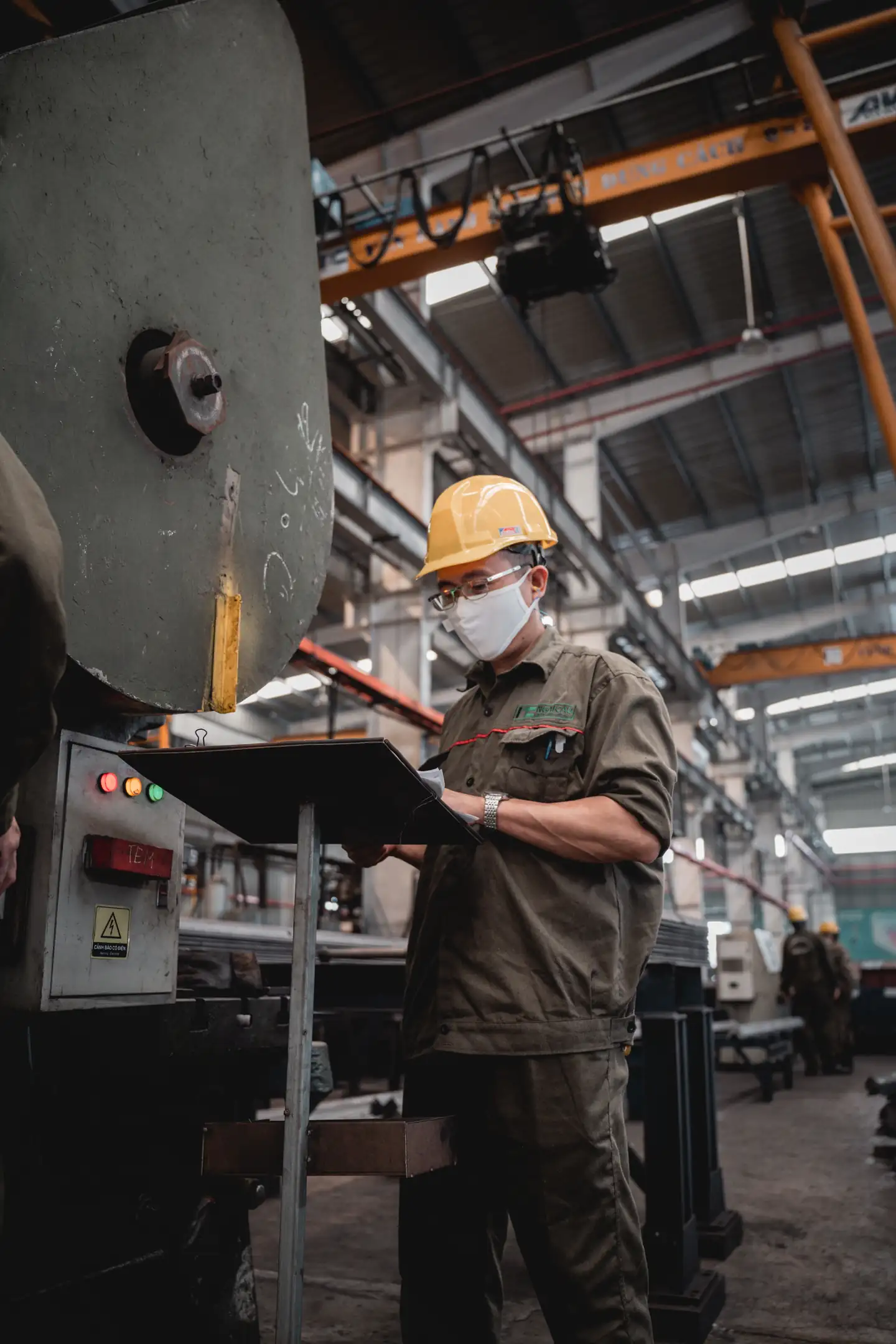 Factory worker consulting a manual at industrial machinery