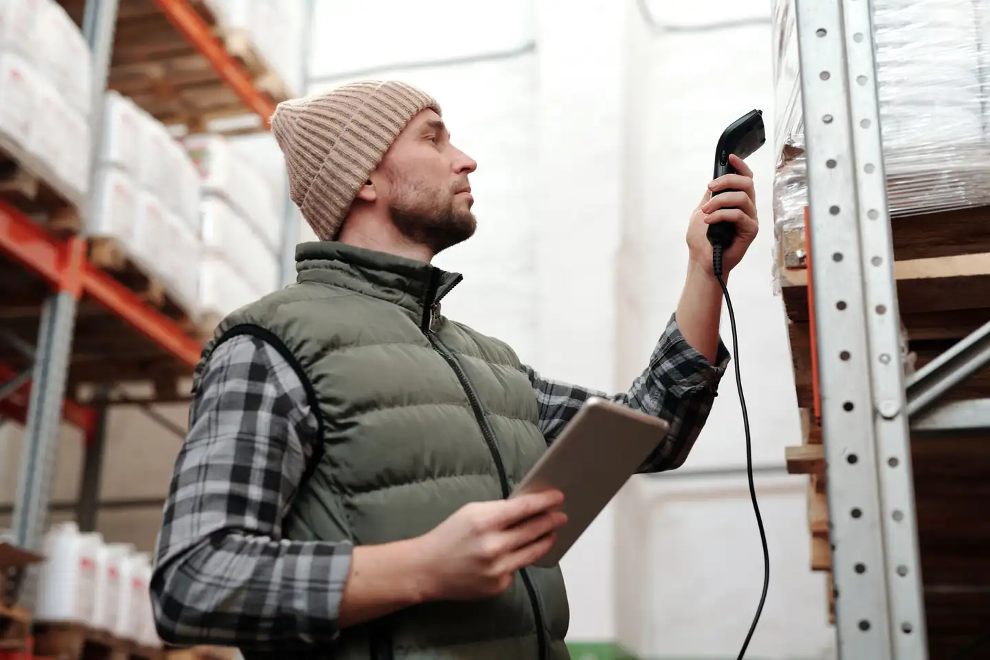 Warehouse employee scanning inventory with a handheld scanner and tablet