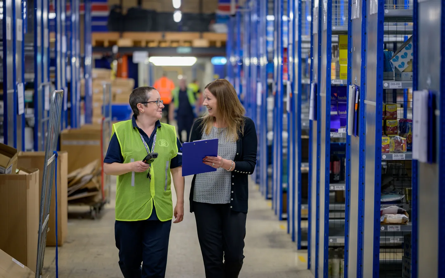Dos empleados revisando registros junto a estanterías del almacén